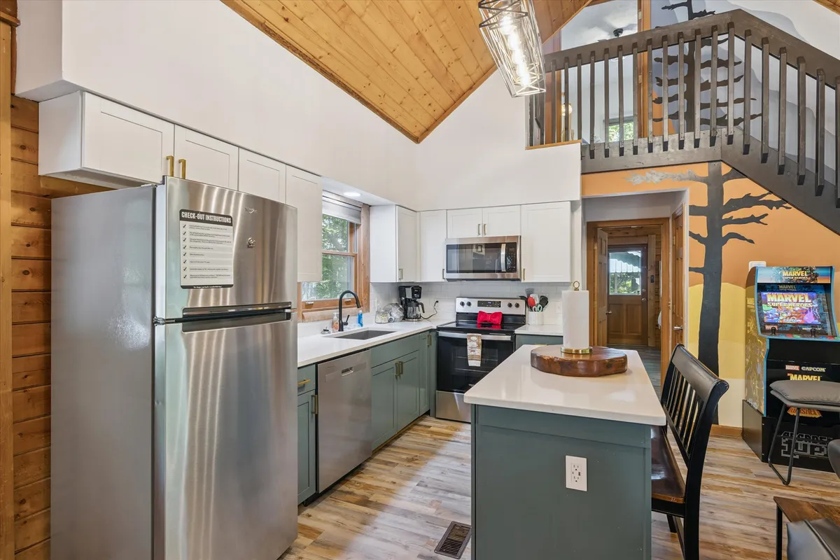This image offers a view of the modern kitchen with a spacious island, stainless steel appliances, and large windows that brighten the space. The colorful wall mural and open design suggest an atmosphere perfect for group cooking, morning coffee, or planning the day's adventures.