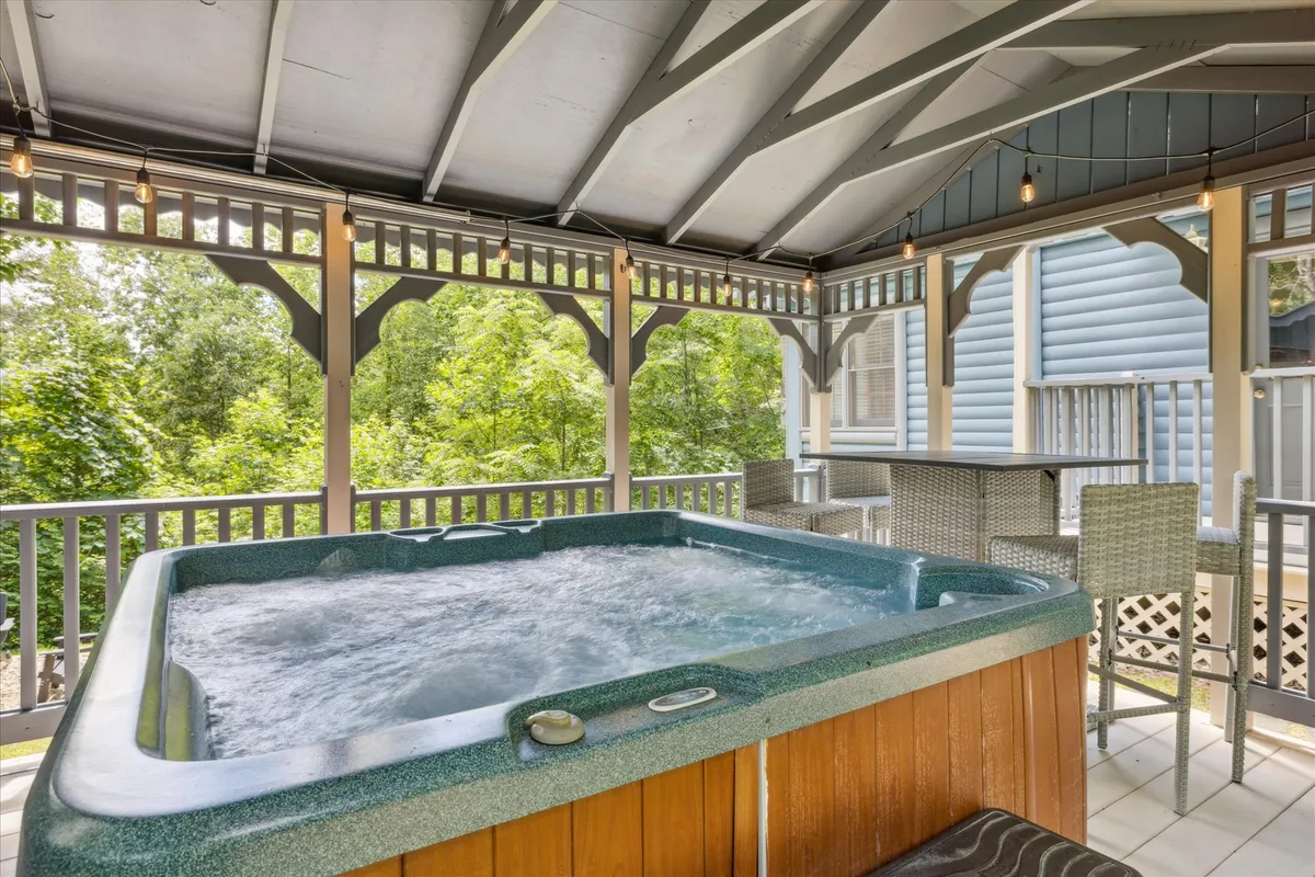 An outdoor hot tub sits on a private deck surrounded by lush greenery, with comfortable seating and soft evening lighting. The scene invites relaxation, conversation, and unwinding after a day of adventure.